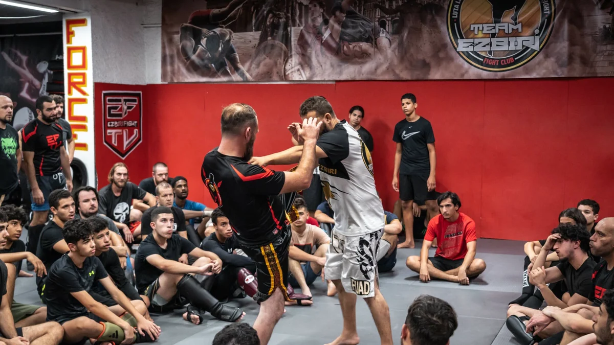 Cours de sport de combat à Team Ezbiri, Villeurbanne, avec un groupe de jeunes pratiquants autour d'une démonstration technique